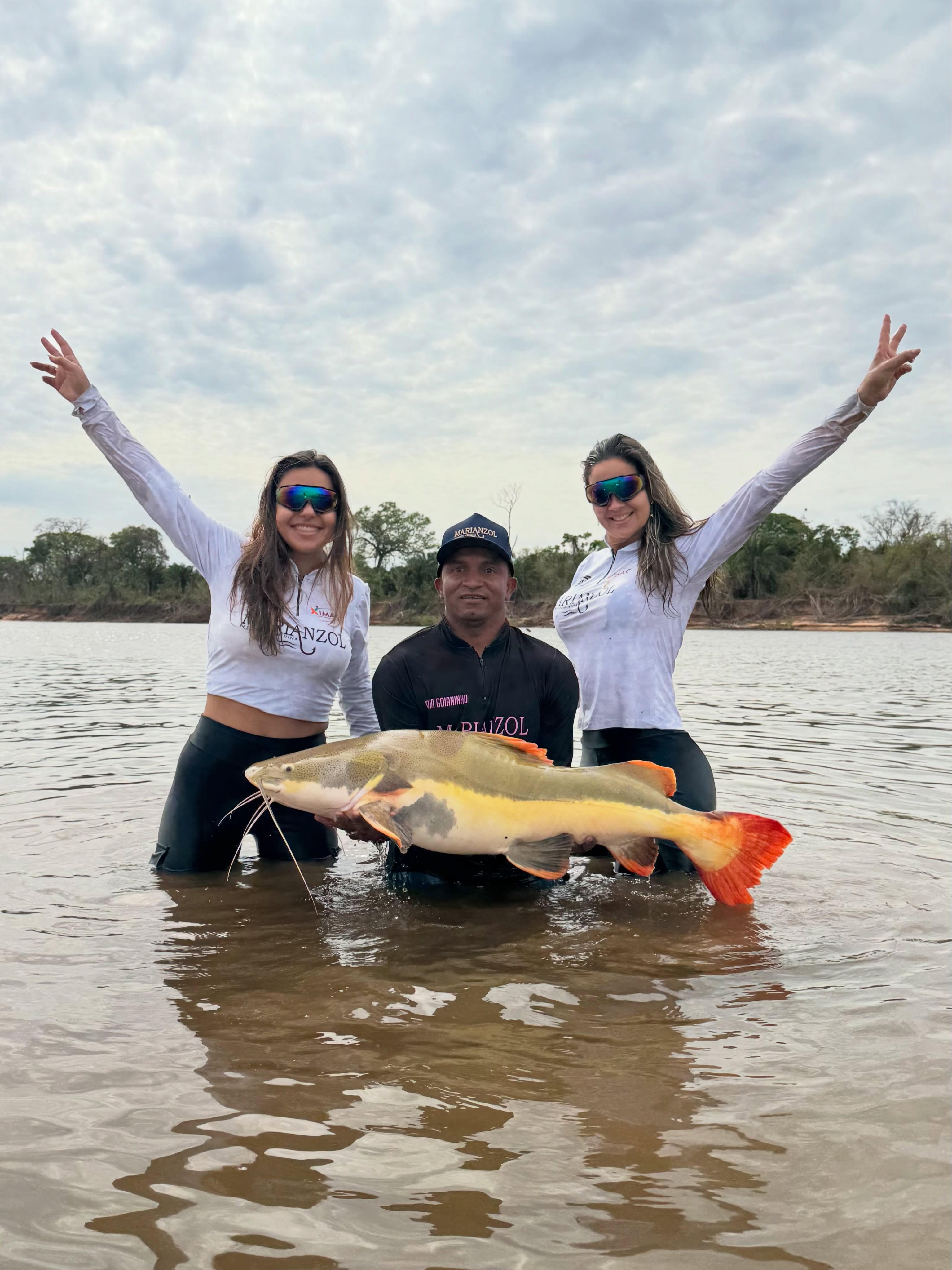 Duas mulheres e um guia na água com um peixe durante uma pescaria da Marianzol