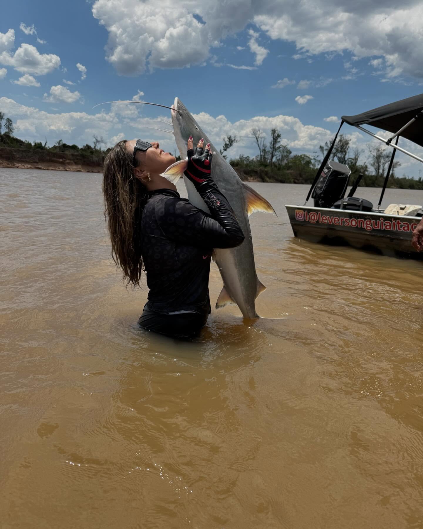 Pescadora na água levantando um peixe